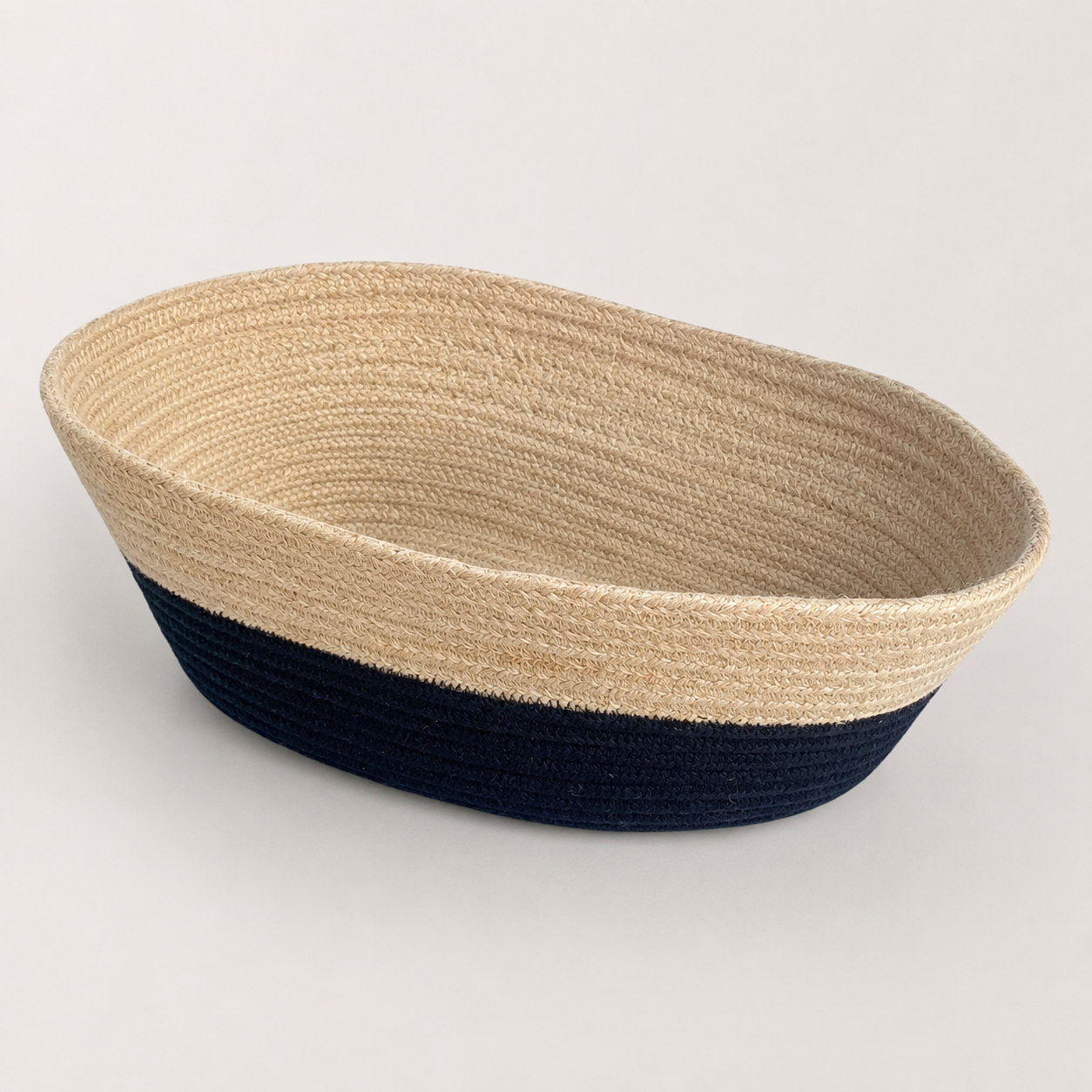 Angled view of boat-shaped beige and black cotton cord fruit basket